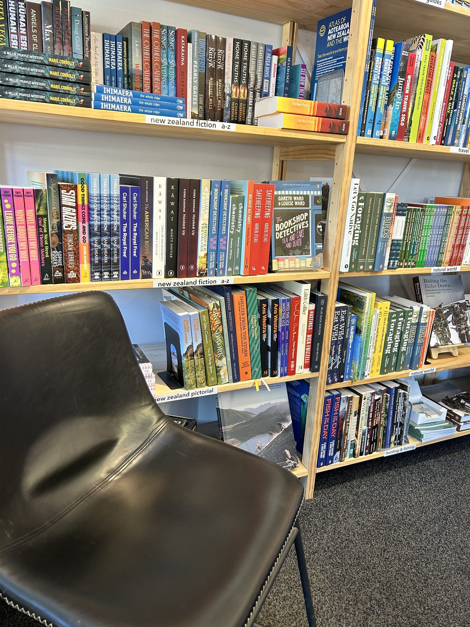 Shelves of New Zealand fiction with a reading chair